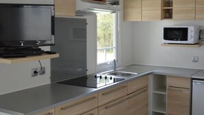 A modern kitchen with stainless steel appliances, wooden cabinets, and a built-in microwave. - Woodland Chalet in the Ardennes (Viroinval)