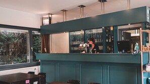 A bar area with a counter, bar stools, and a seating area with tables and chairs. - Woodland Chalet in the Ardennes (Viroinval)