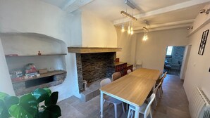 A dining area with a wooden table and chairs, a brick fireplace, and hanging light fixtures. - Maison pic Saint Loup (Viols-le-Fort)