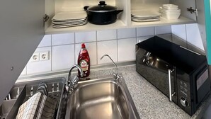 Eine Küche mit weißen Schränken, einer Edelstahl-Spüle und einer schwarzen Mikrowelle.