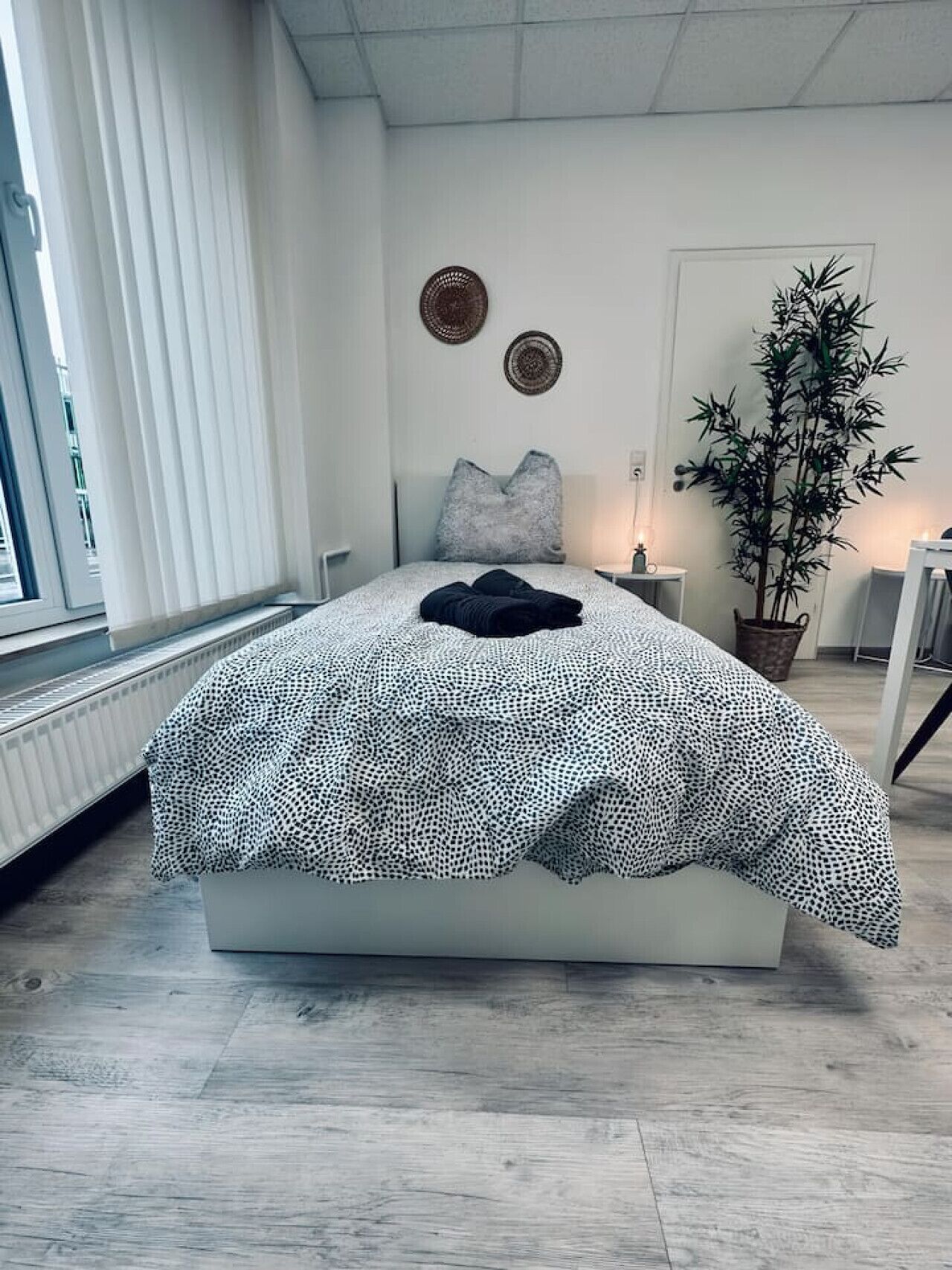 Un dormitorio moderno con una cama, una planta en maceta y un ventanal.