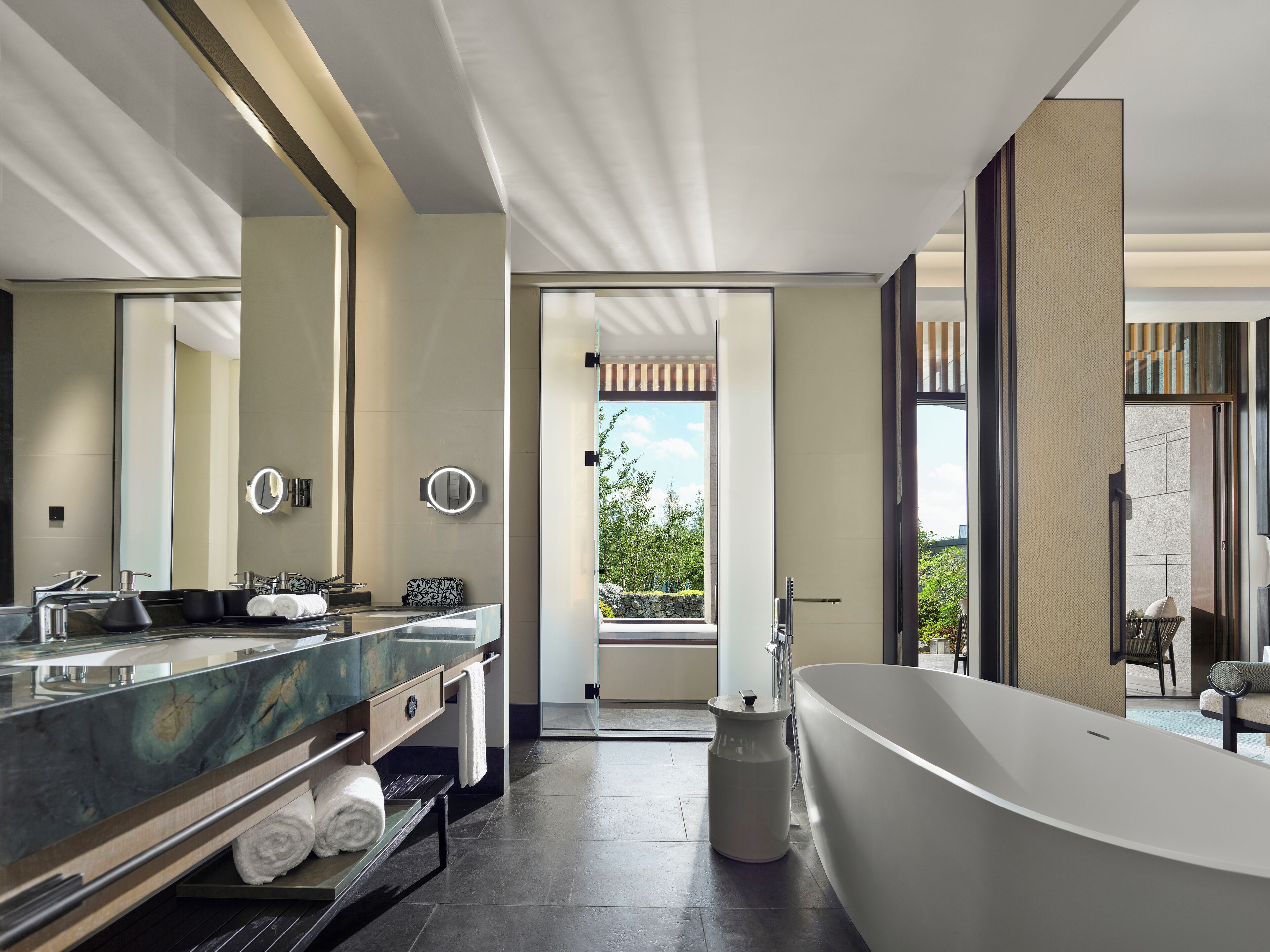 A modern bathroom with a large bathtub, dual sinks, and a large mirror.