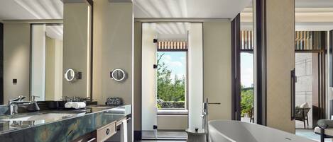 A modern bathroom with a large bathtub, dual sinks, and a large mirror.