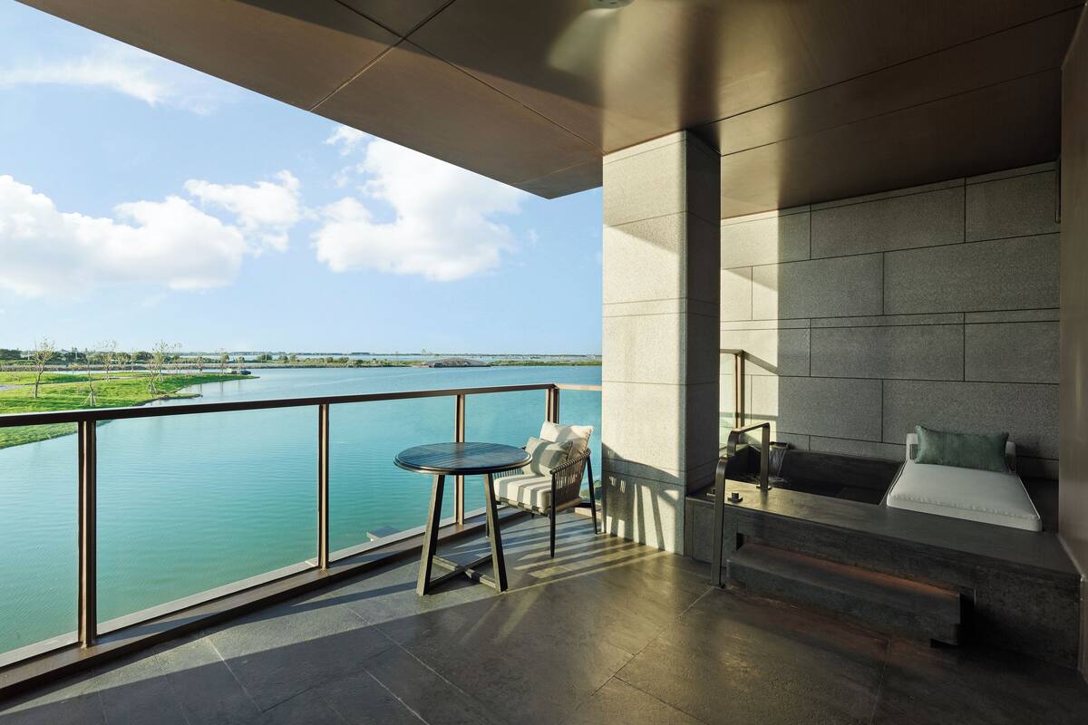 A modern balcony with a view of a river and distant landscape.