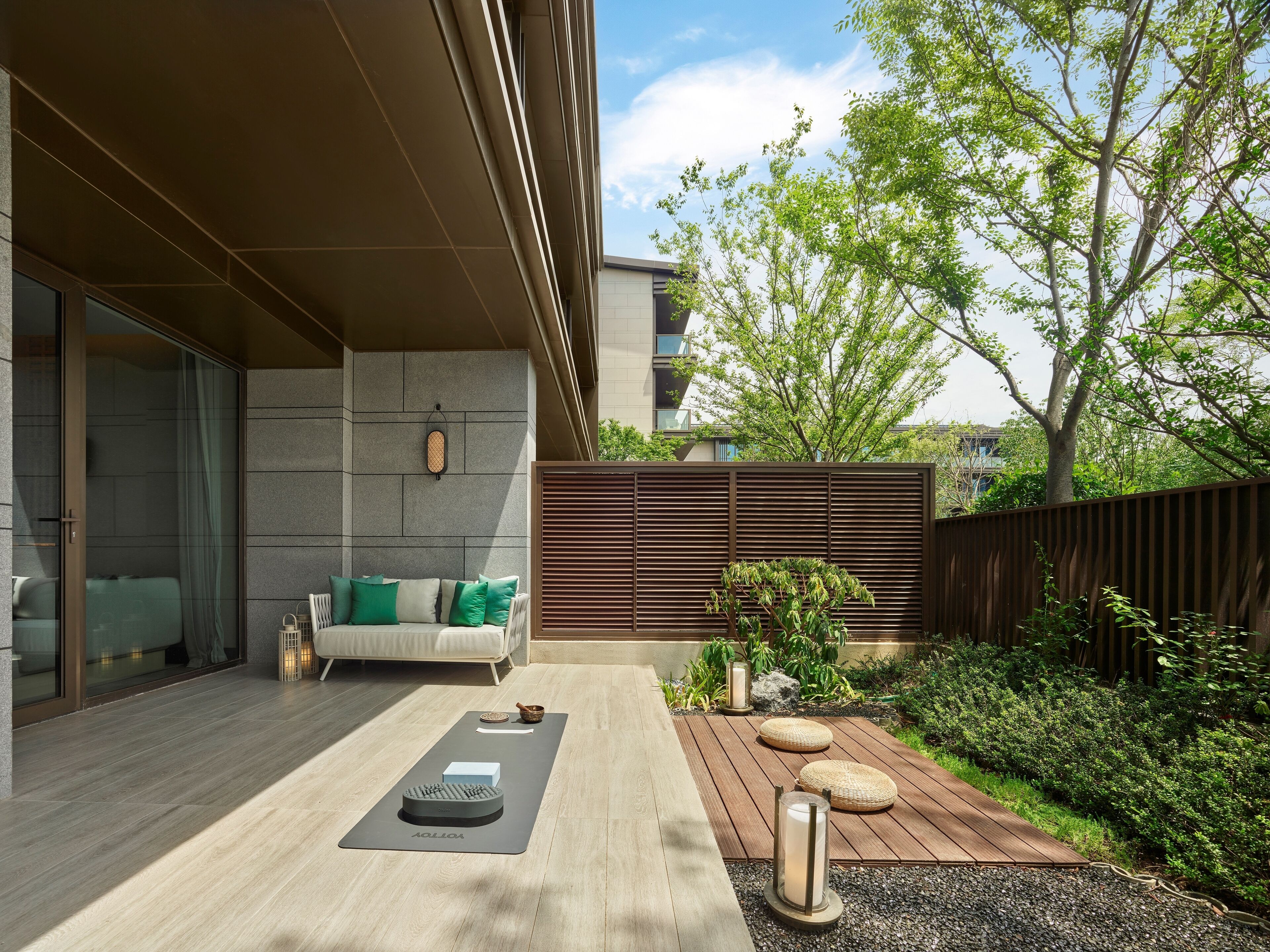 A modern outdoor living area with a wooden deck, a yoga mat, and a meditation bench.