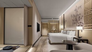 Een moderne hotelkamer met een bed, een bureau, een stoel, een televisie en decoratieve wand.