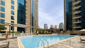 Une piscine dotée d’une terrasse carrelée, entourée d’immeubles de grande hauteur.
