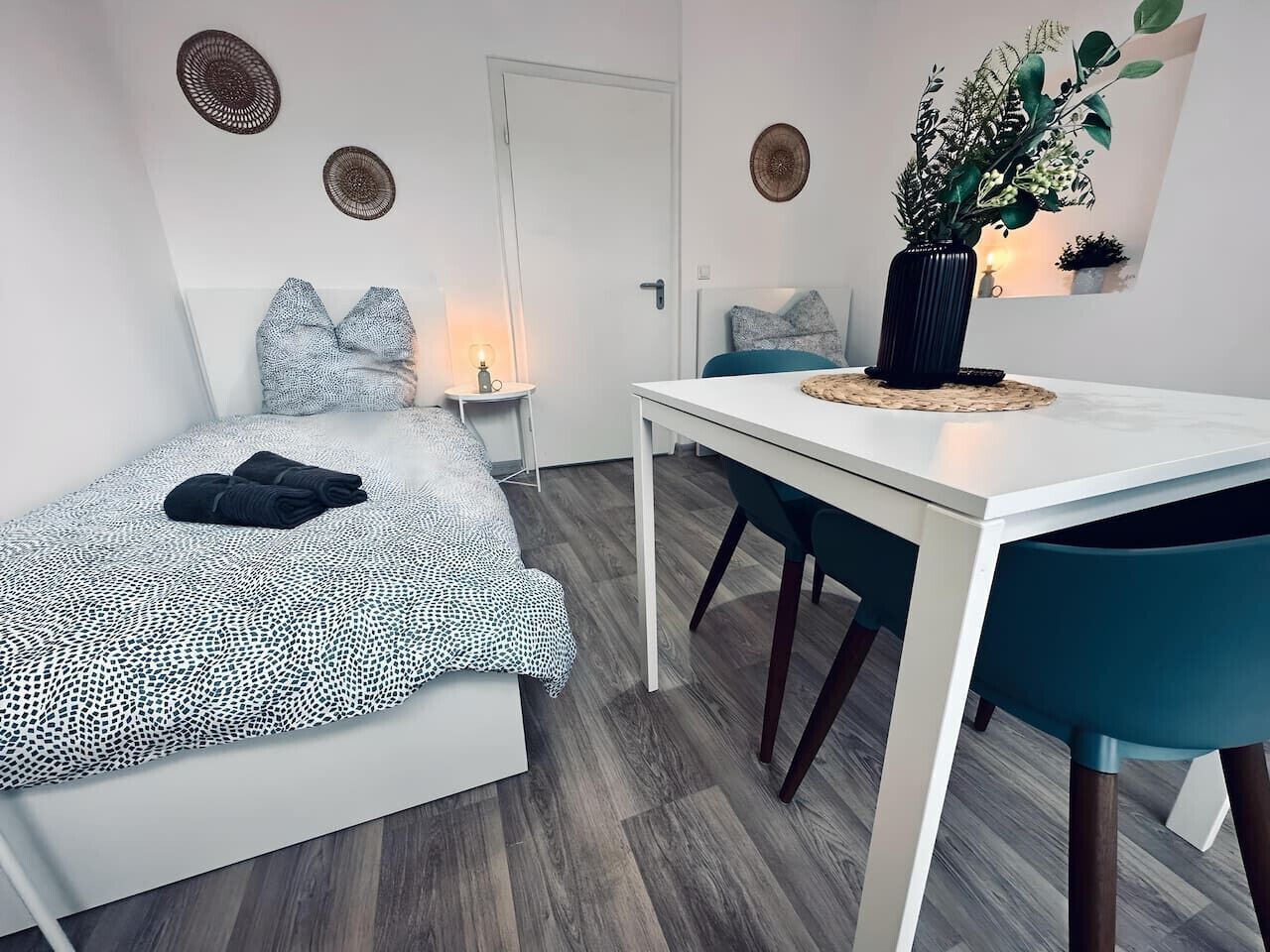 Un dormitorio con cama, mesitas de noche, escritorio y silla.