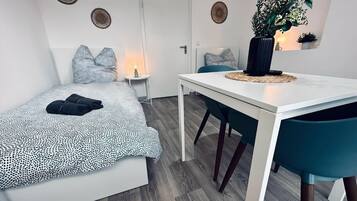 Un dormitorio con cama, mesitas de noche, escritorio y silla.