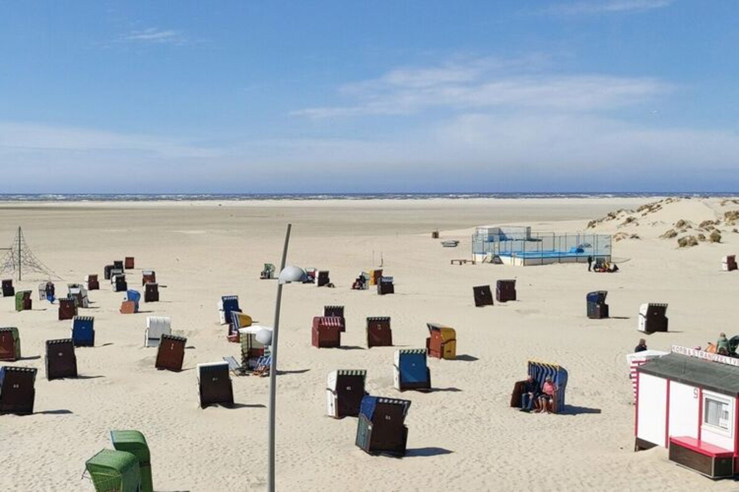 Una playa con numerosas cabañas de playa coloridas y una torre de salvavidas al fondo.