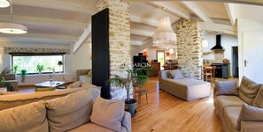 A spacious living area with a high ceiling, stone walls, and wooden flooring. There are multiple seating areas with sofas and a coffee table. - Charm, calm and pleasure in the Provencal countryside, not far from Sisteron (Châteauneuf-Val-Saint-Donat)