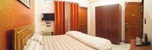 A hotel room with a bed, a television, a wardrobe, and a kettle on the table. - Kalp Taru Residency By GRB (Greater Noida)