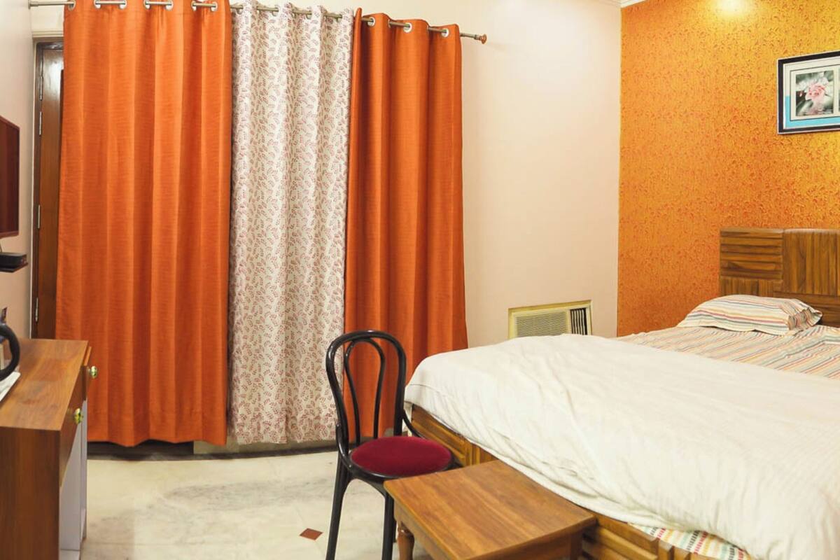 Une chambre d’hôtel avec un lit, un bureau, une chaise, un tableau au mur et un rideau de douche.