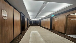 Un pasillo de hotel con paneles de madera, suelo de baldosas y señal de salida.