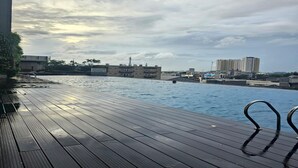 Una terraza de madera con vista a un cuerpo de agua y edificios al fondo.