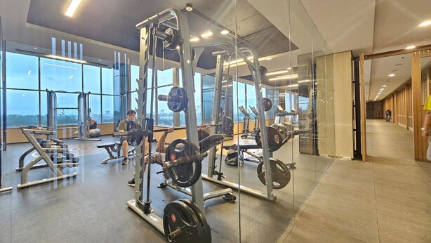 Un gimnasio con equipo de levantamiento de pesas, ventanas amplias y un diseño interior moderno.