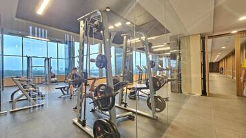 A gym with weightlifting equipment, large windows, and a modern interior design.
