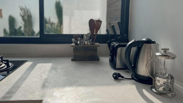 Eine Küchenarbeitsplatte mit Kaffeemaschine, Wasserkocher und einem Glasbehälter.