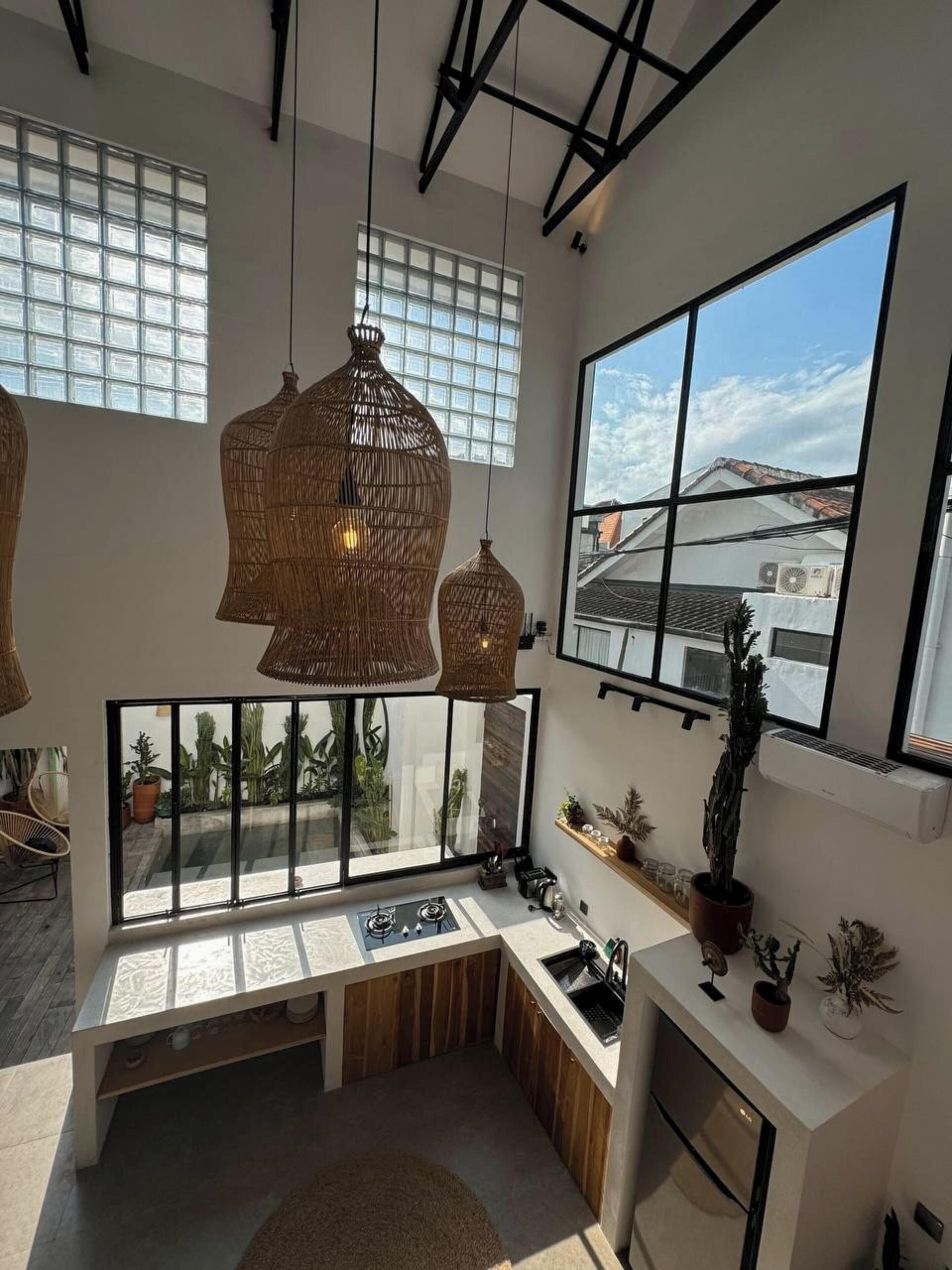 Una cocina moderna con un gran ventanal, un banco empotrado y lámparas colgantes de mimbre.