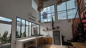 A modern kitchen with large windows, a built-in bench, and a dining area with a wooden table and chairs.