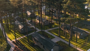 Luchtbeeld van een woonwijk met huizen, bomen en een heldere lucht.