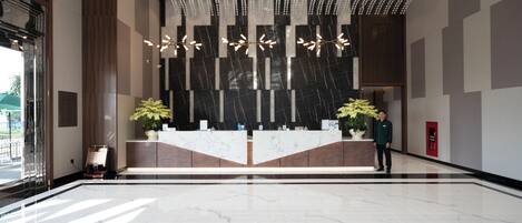 A modern reception area with a marble reception desk, potted plants, and a decorative ceiling.