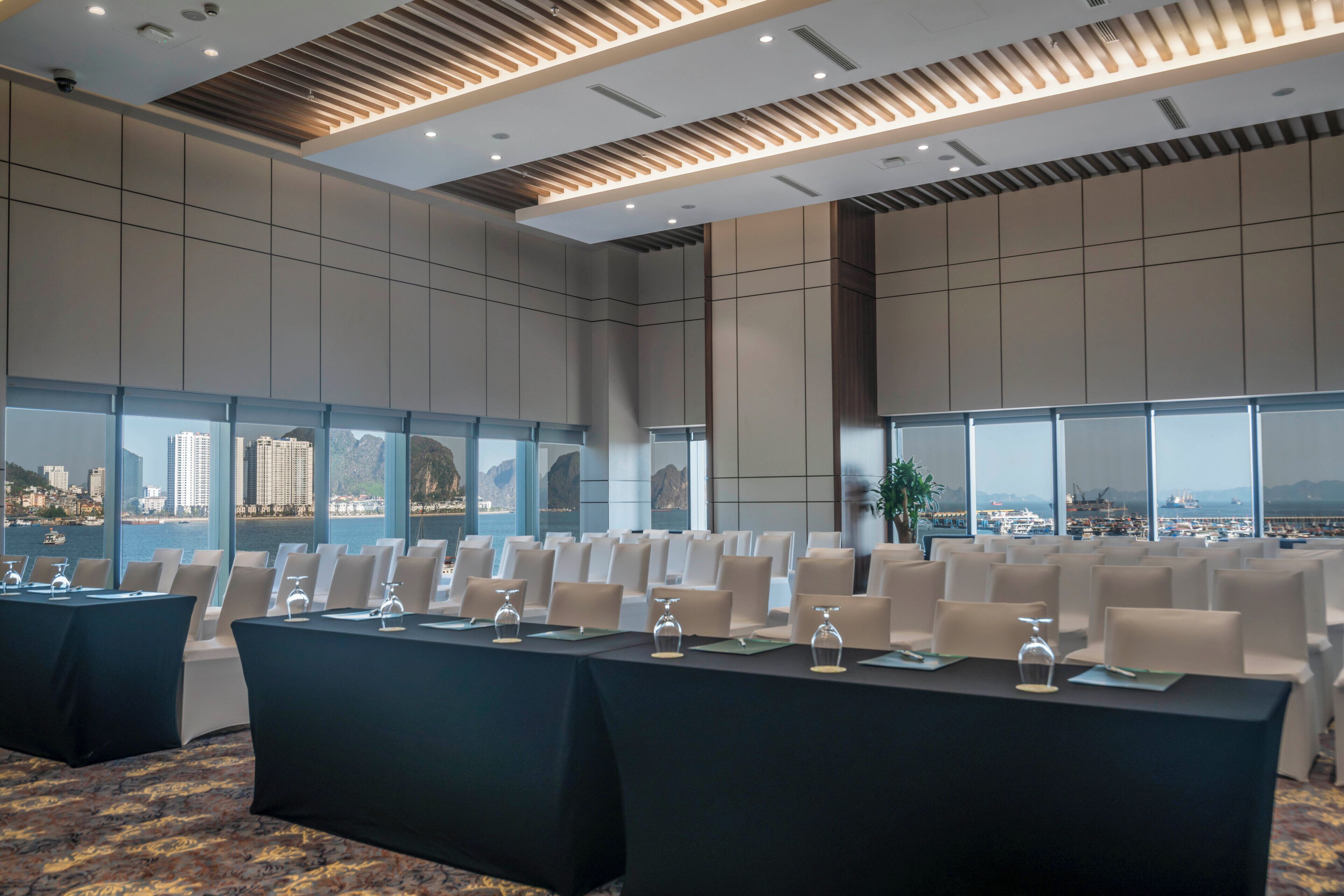 Une salle de conférence dotée d’une longue table, de nombreuses chaises et de grandes fenêtres donnant sur la ville.