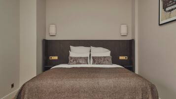 A neatly made bed with a brown checkered bedspread and two pillows, flanked by wall-mounted light fixtures.