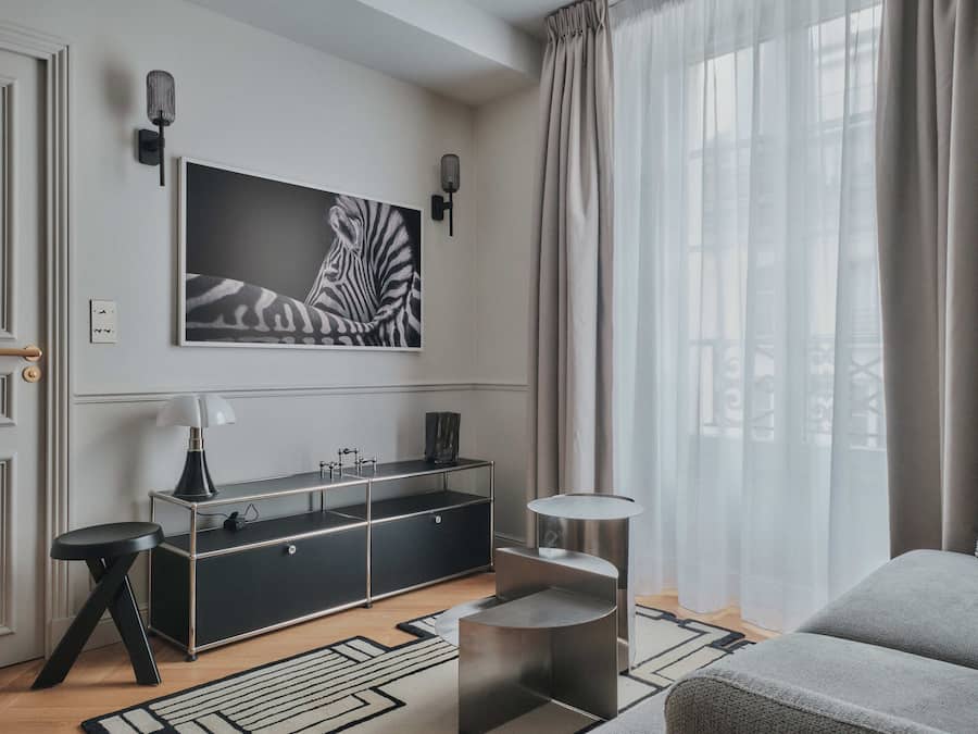 Una sala de estar moderna con un sofá, una mesa de centro, una consola negra con una lámpara y una obra de arte grande con estampado de cebra en la pared.