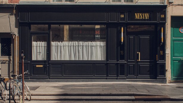 Une devanture de magasin noire avec l’enseigne « NESTAY » et le numéro « 158 ».