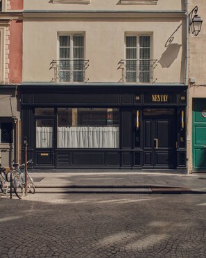 Une devanture de magasin noire avec l’enseigne « NESTAY » et le numéro « 158 ».