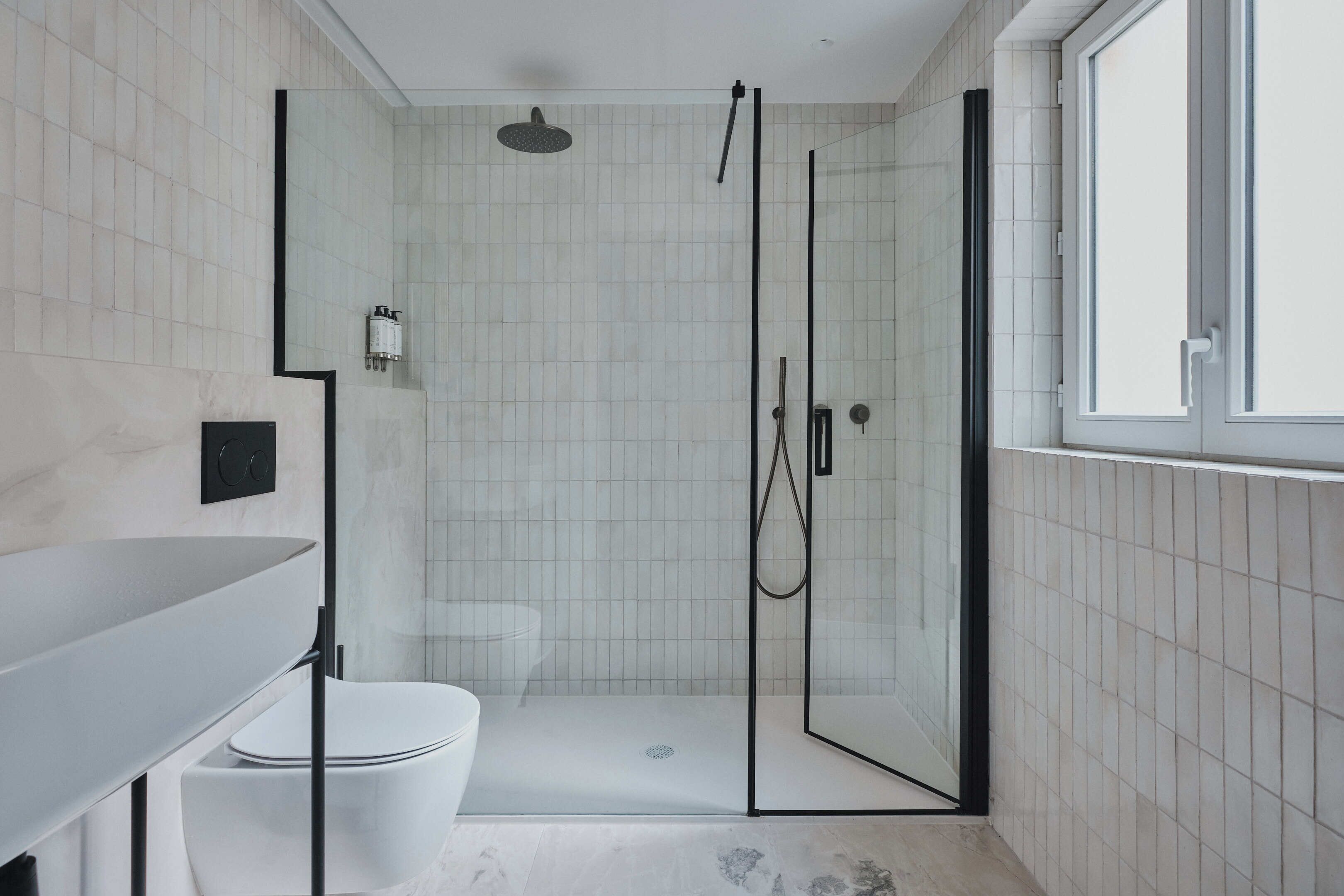 A modern bathroom with a glass-enclosed shower, a white toilet, and a vanity with a mirror.