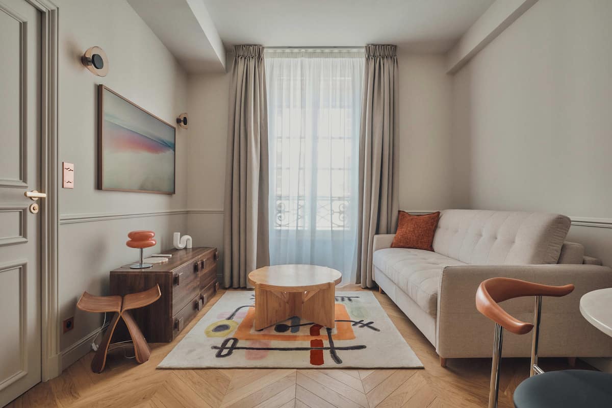 A modern living room with a sofa, a round wooden coffee table, a side table, and a chair.