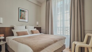 Une chambre d’hôtel bien aménagée, avec un grand lit, une chaise, une table de chevet et une fenêtre avec des rideaux.