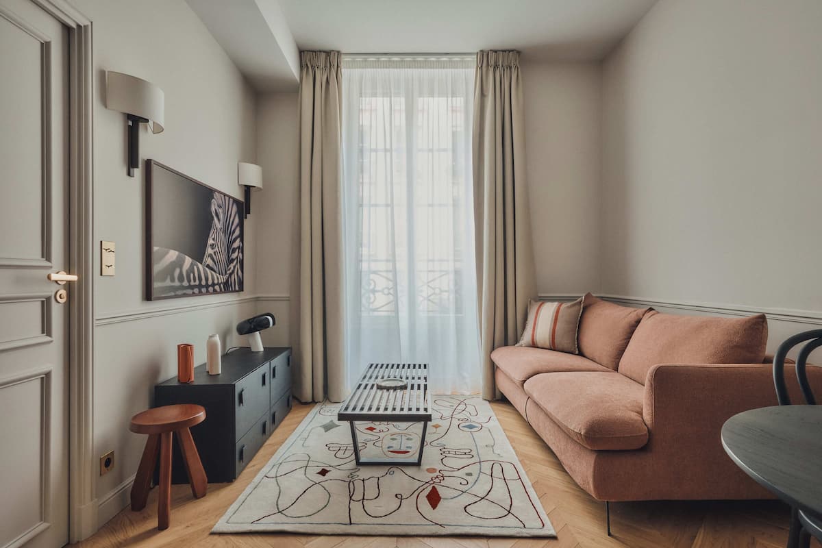 A modern living room with a sofa, a coffee table, a small stool, and a rug with abstract designs.