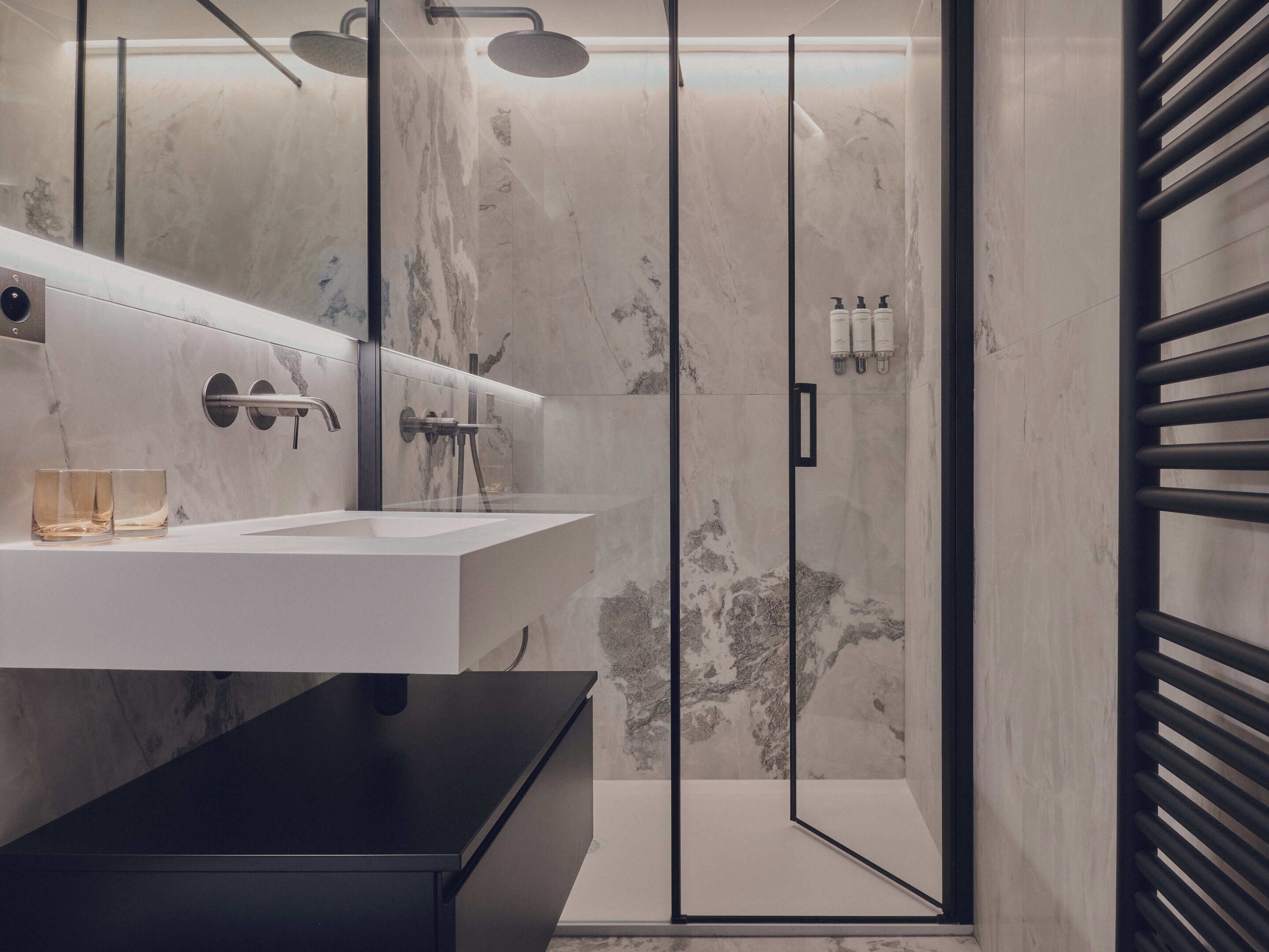 A modern bathroom with a glass-enclosed shower, a white sink, and a black countertop.