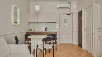 A compact kitchen with a white countertop, a round dining table, and a sofa.