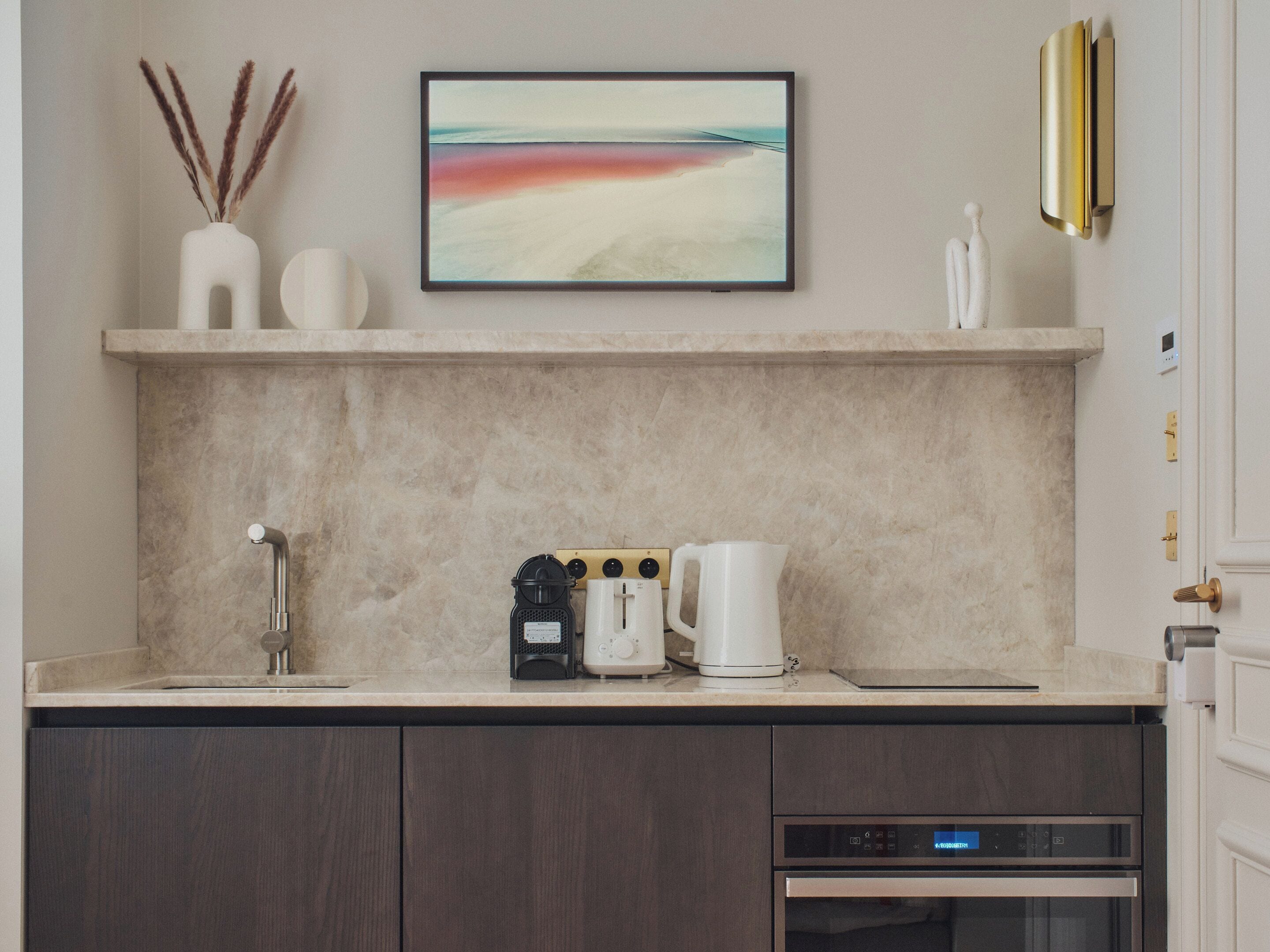 A modern kitchen with a marble countertop, a coffee maker, a kettle, and a toaster.