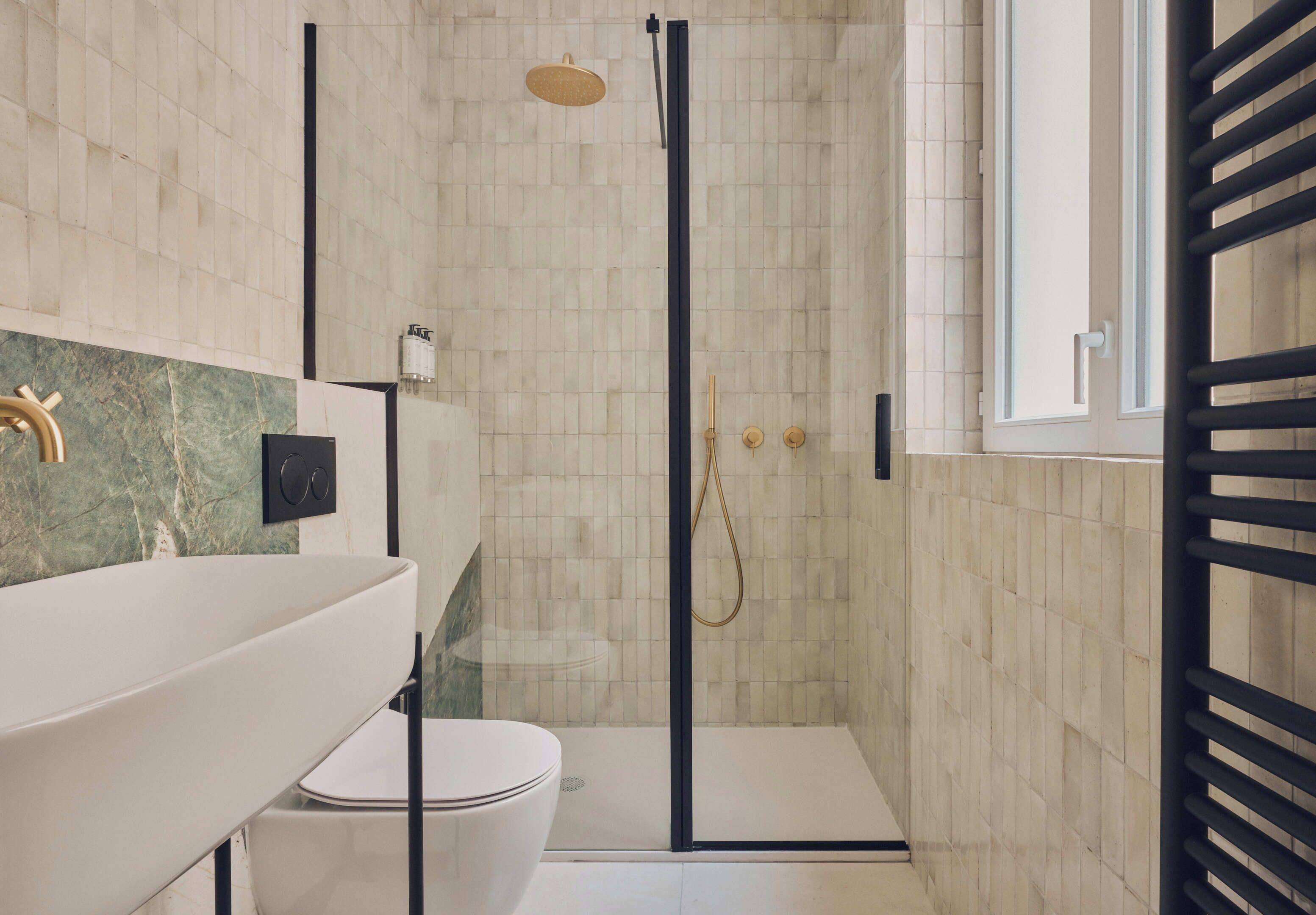 A modern bathroom with a glass-enclosed shower, a white sink, and a marble countertop.