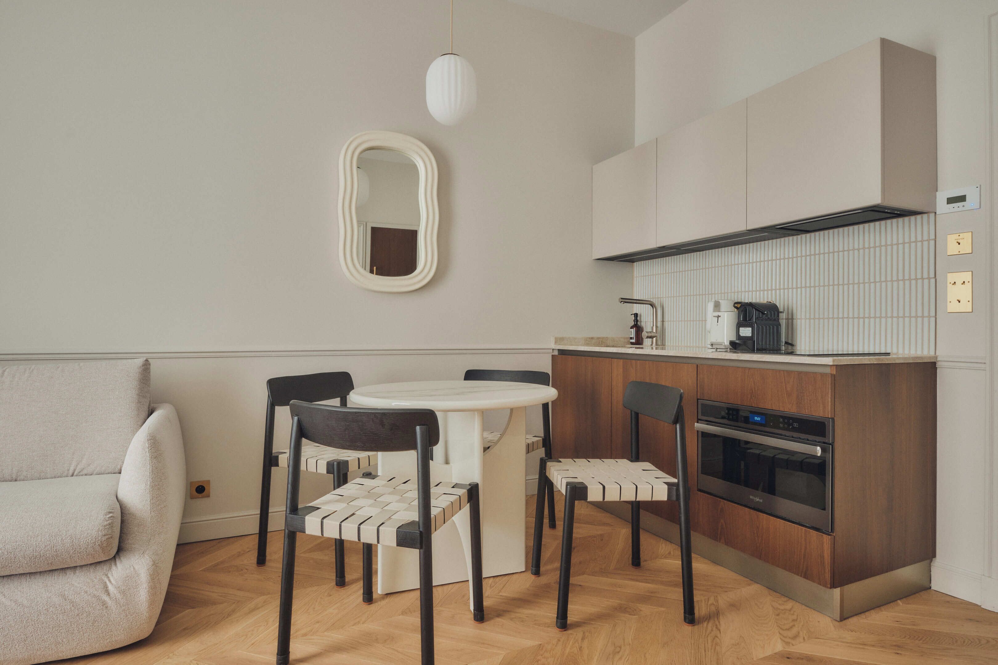 Una cocina compacta con una mesa redonda, cuatro sillas, un sofá y una lámpara colgante moderna.