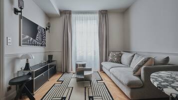 A modern living room with a grey sofa, a black and white patterned coffee table, a black floor lamp, and a black and white rug.