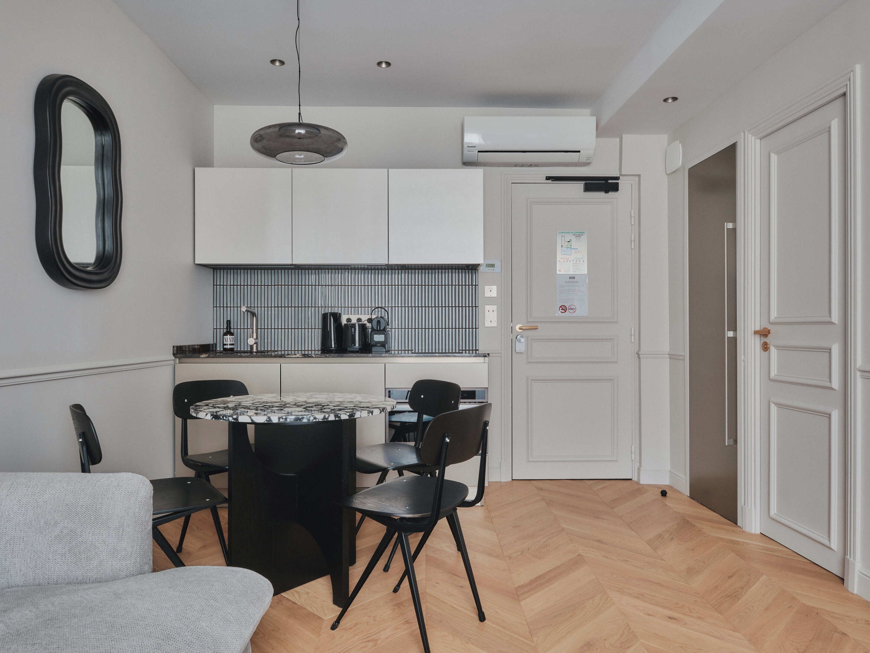 A compact kitchen with white cabinets, a round dining table, and black chairs.