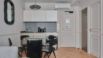 A compact kitchen with white cabinets, a round dining table, and black chairs.