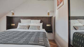 Una cama bien hecha con una colcha estampada, cabecera de madera, lámparas de noche y un aire acondicionado instalado en la pared.