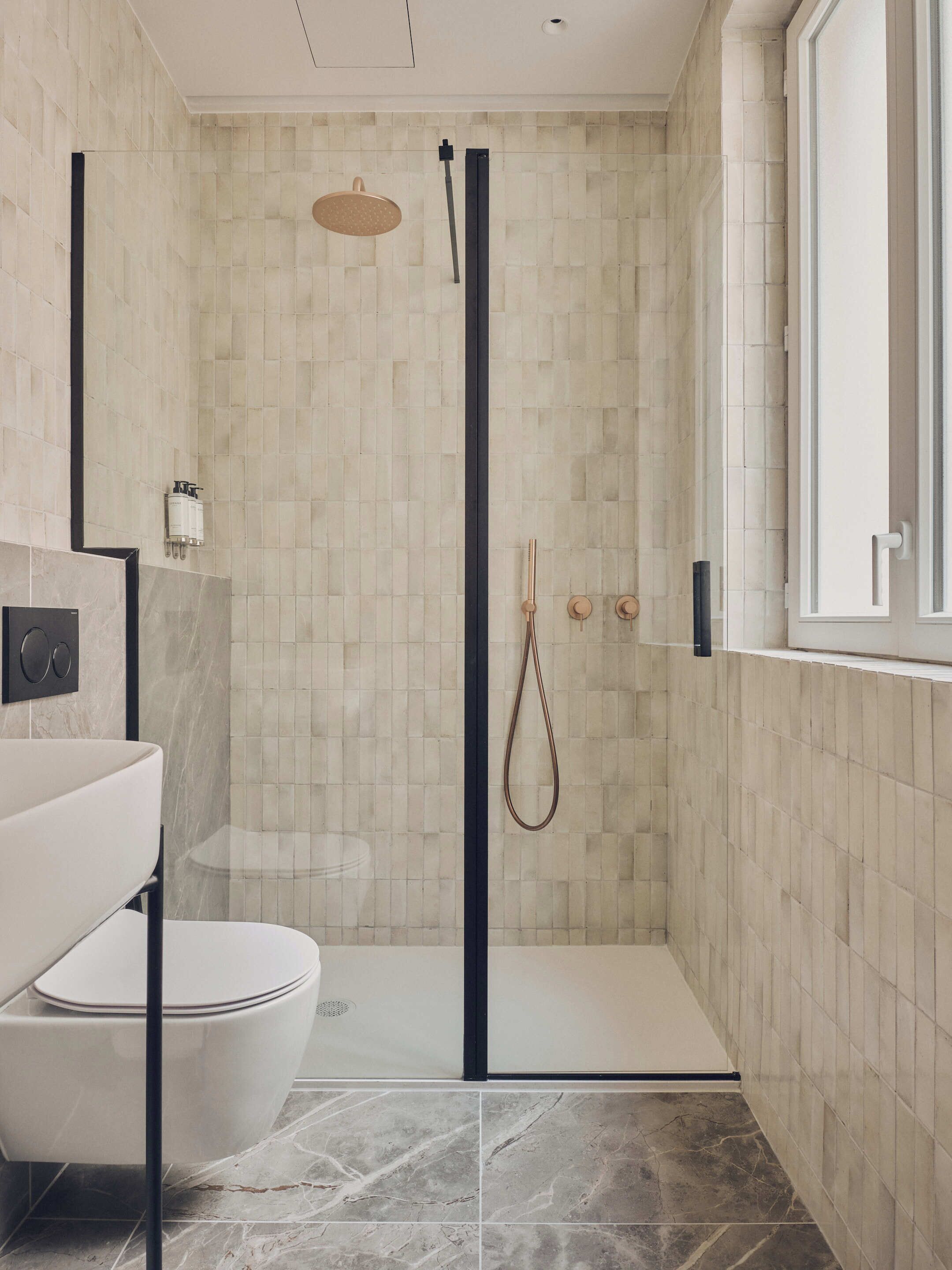 A modern bathroom with a shower, toilet, and sink.