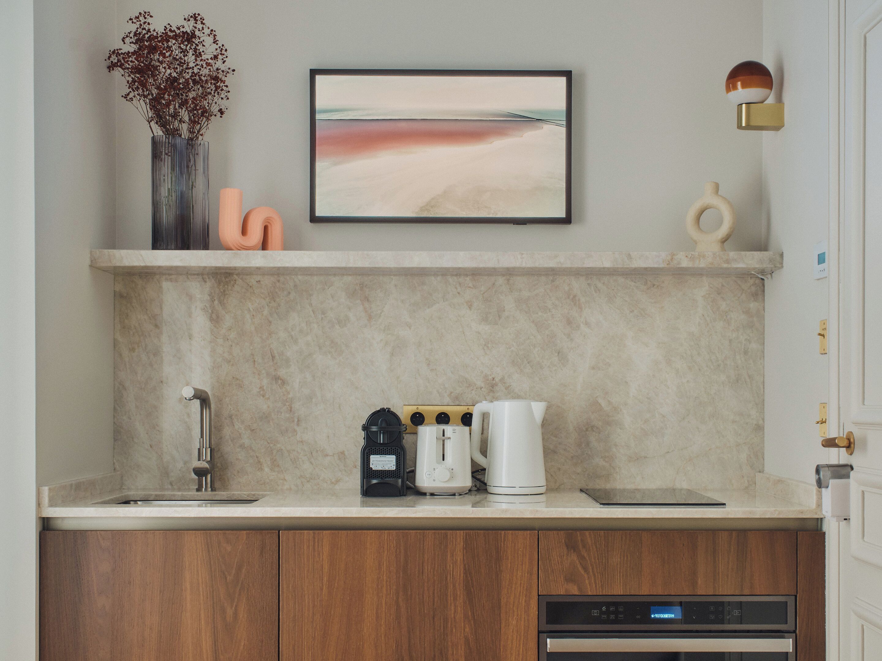 Una cocina con encimera de mármol, cafetera, hervidor de agua y lavavajillas.