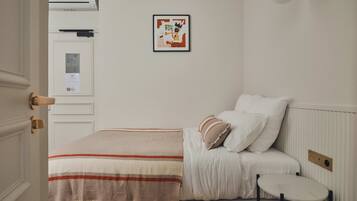 A bedroom with a bed, a bedside table, a framed picture on the wall, and a radiator.