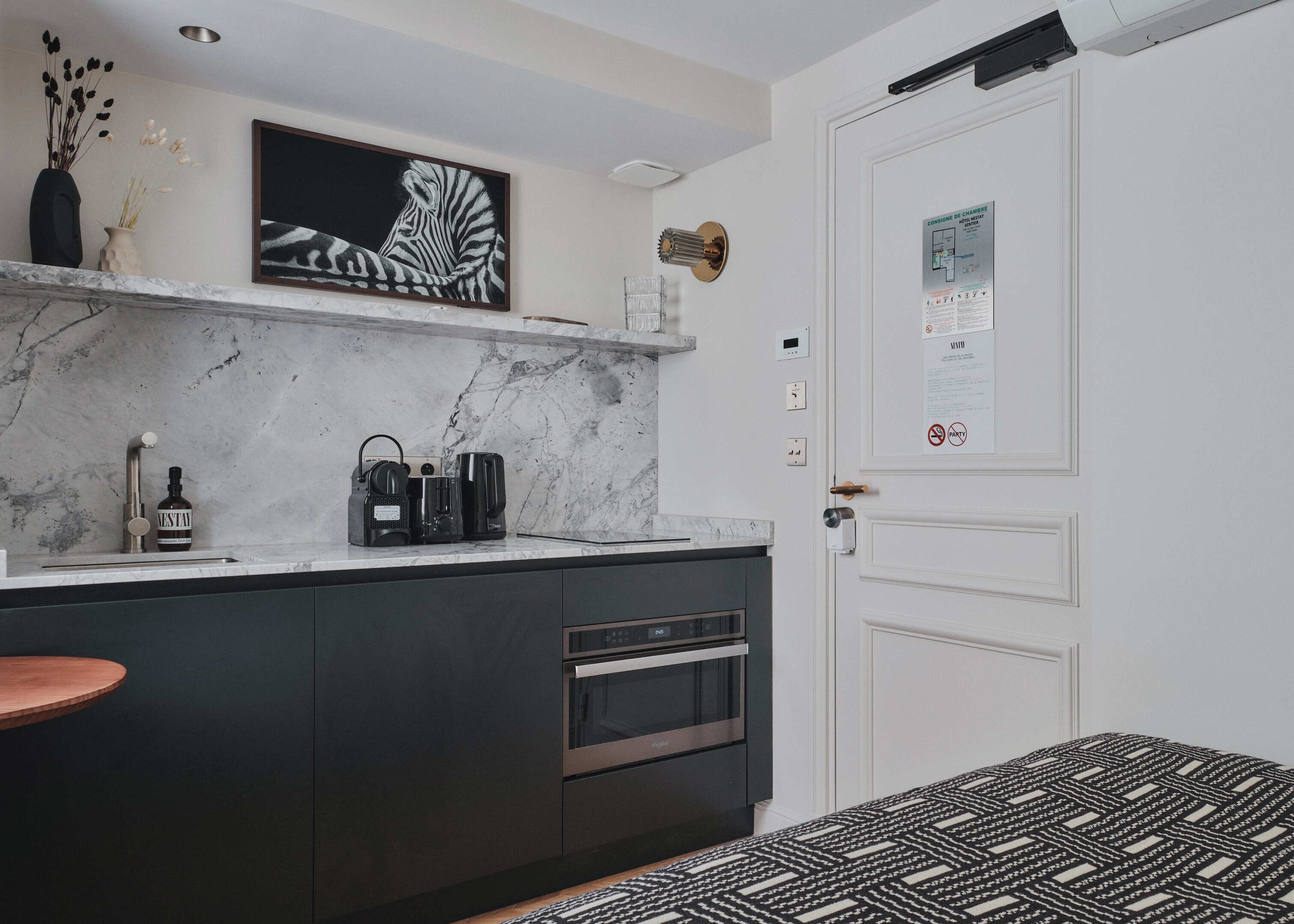 A modern kitchen with a marble countertop, a coffee machine, and a wine bottle.