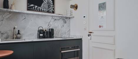 A modern kitchen with a marble countertop, a coffee machine, and a wine bottle.