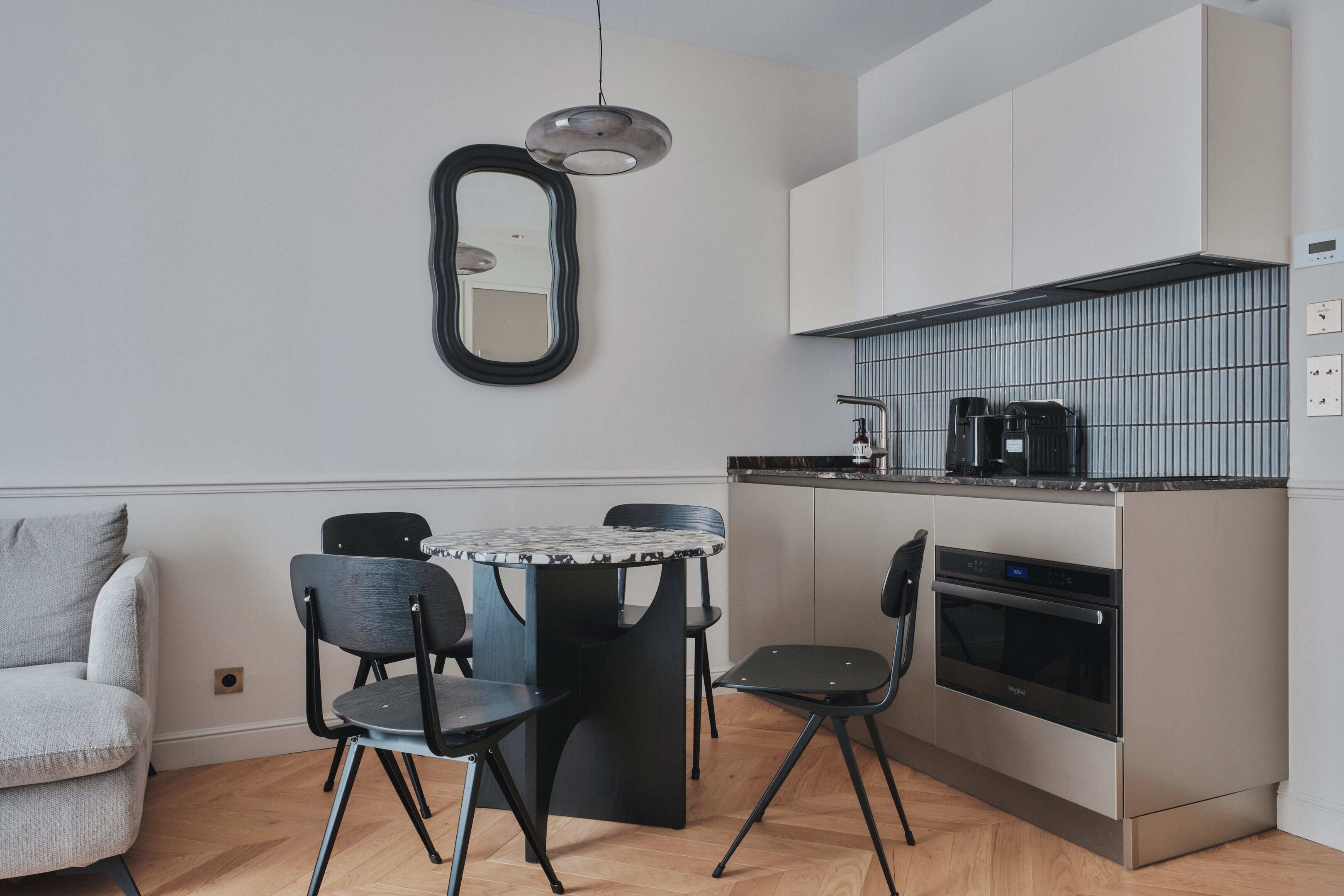 Una cocina compacta con comedor, un sofá y un espejo en la pared.